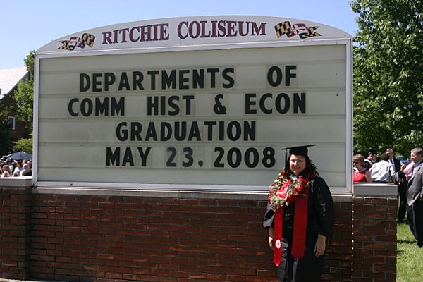 Posing by the sign to mark graduation day.